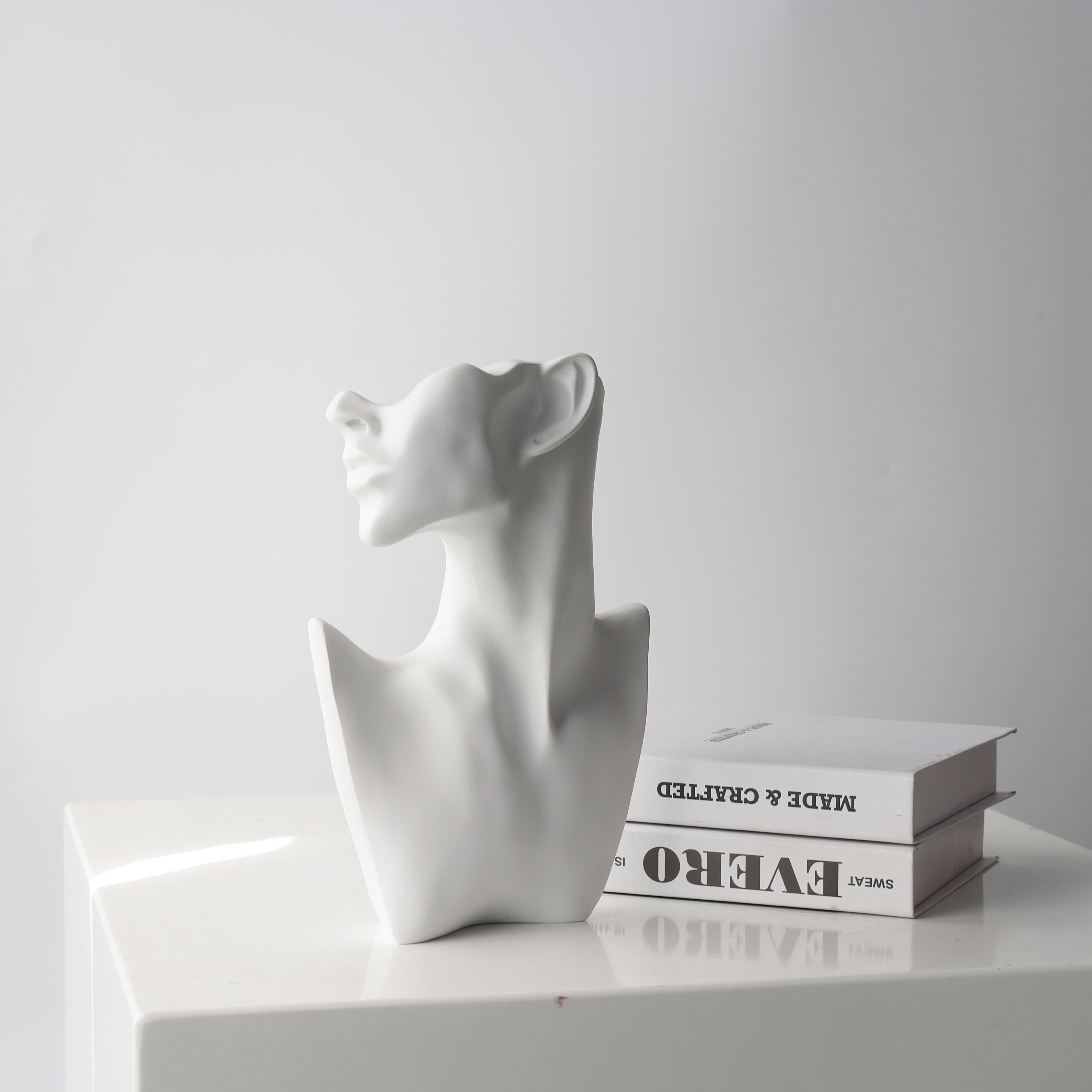 Eve abstract face sculpture by BAG&BONES styled on a console table with design books in a contemporary interior.