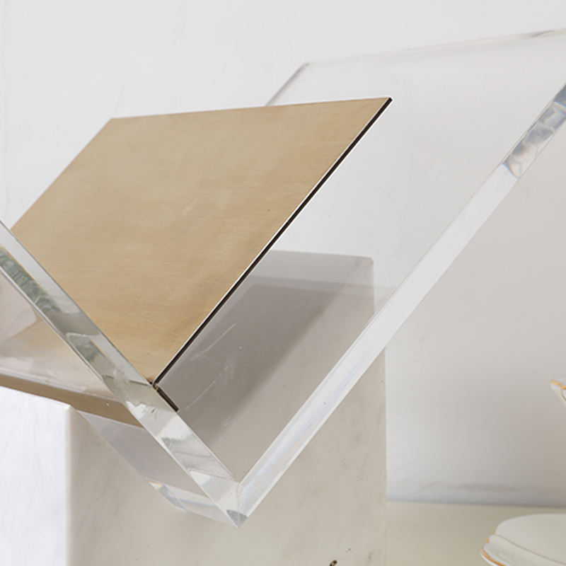Detail of the clear acrylic frame and brushed brass shelf on the Folio magazine holder by BAG&BONES.