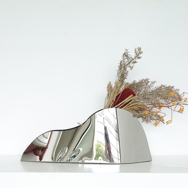 Horizon sculptural vase by BAG&BONES styled with dried stems, featuring a polished stainless steel finish and fluid contemporary silhouette.