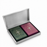 Open brushed silver metal playing card case containing green and magenta ornate card decks with gold detailing.