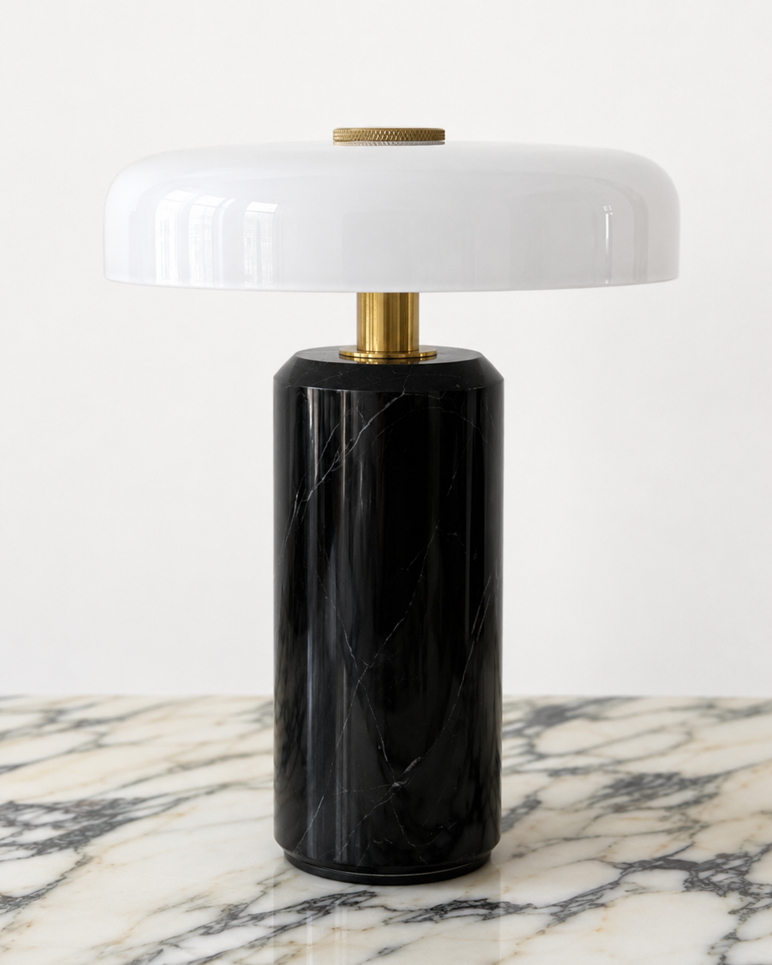 Design-led Muse table lamp featuring a black marble base, brass detailing and a glossy white rounded shade.