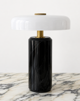 Design-led Muse table lamp featuring a black marble base, brass detailing and a glossy white rounded shade.