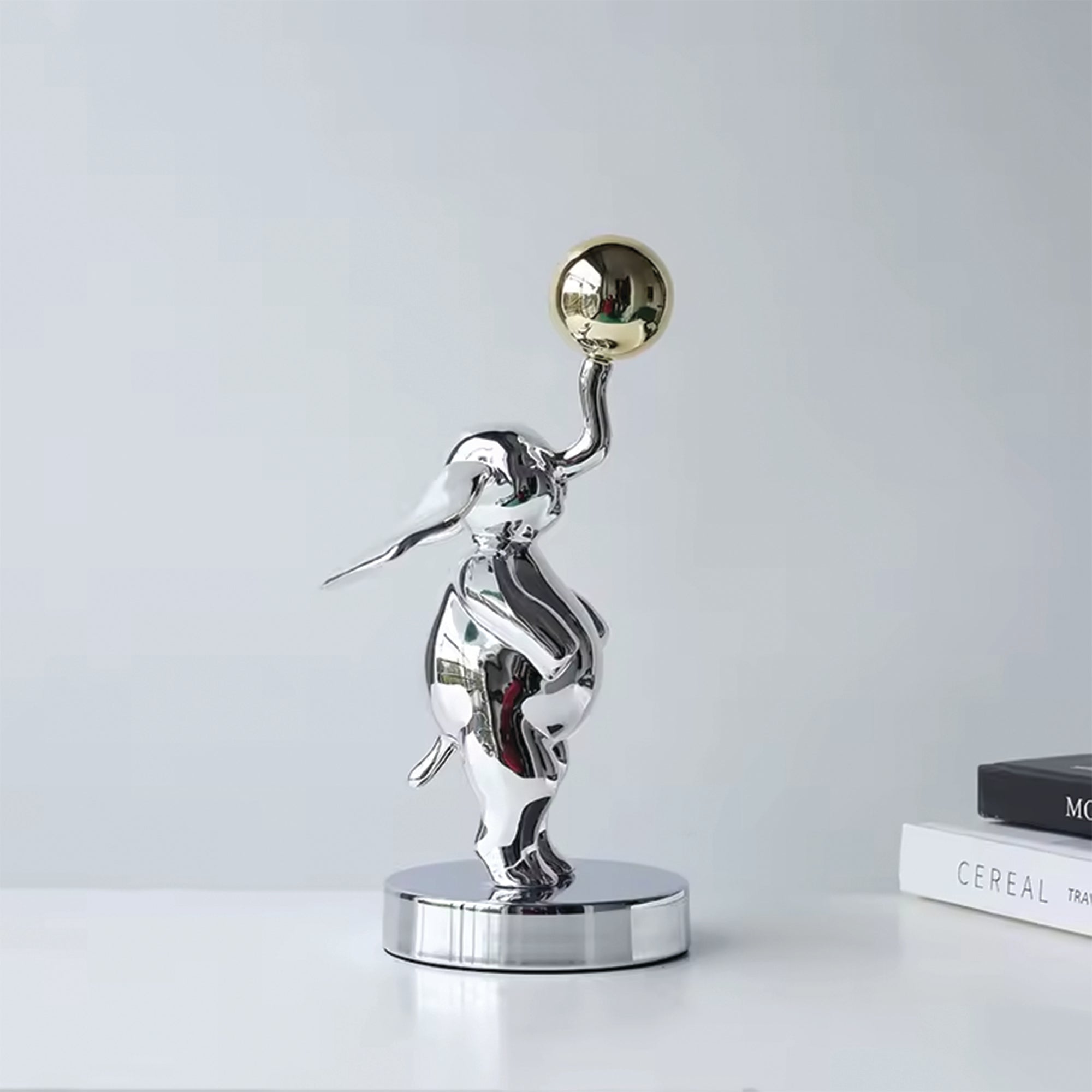 Balance contemporary sculpture by BAG&BONES styled on a shelf, featuring a polished silver figure balancing a gold sphere in a modern interior.