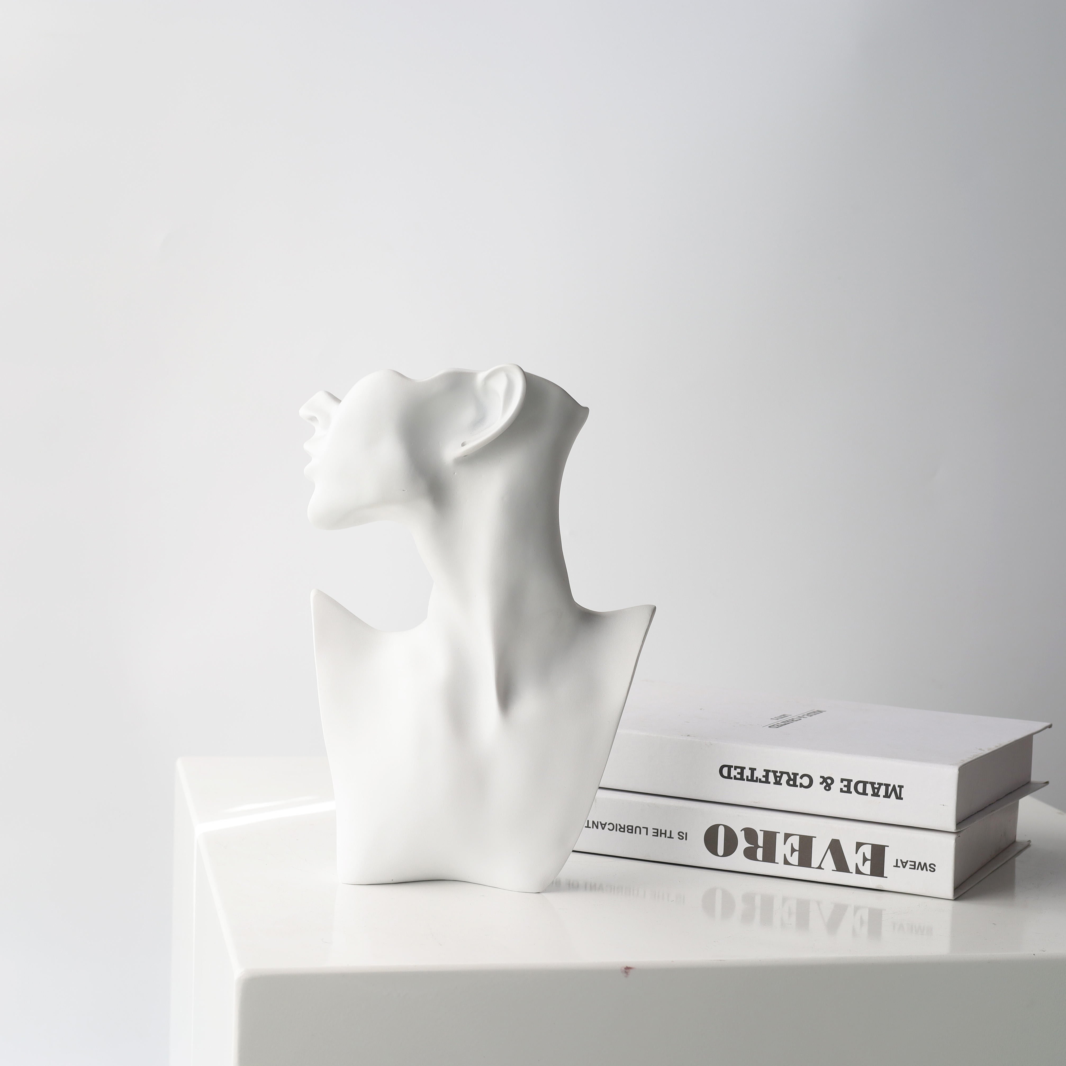 Eve contemporary sculptural bust by BAG&BONES displayed on a tabletop beside design books, adding a minimalist decorative accent to a modern interior.