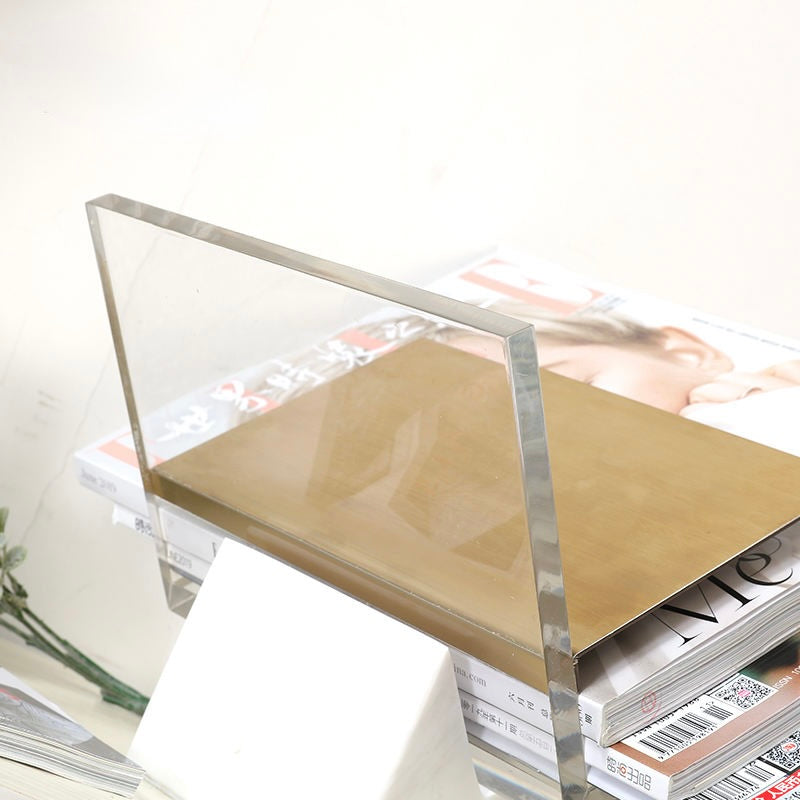 Folio magazine holder by BAG&BONES displaying magazines on a white marble base with a clear acrylic frame and brushed brass shelf.
