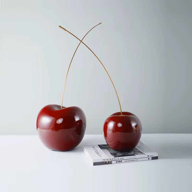 The Cherry decorative sculpture by BAG&BONES styled on a coffee table with books, featuring glossy red cherries with gold stems in a contemporary interior.