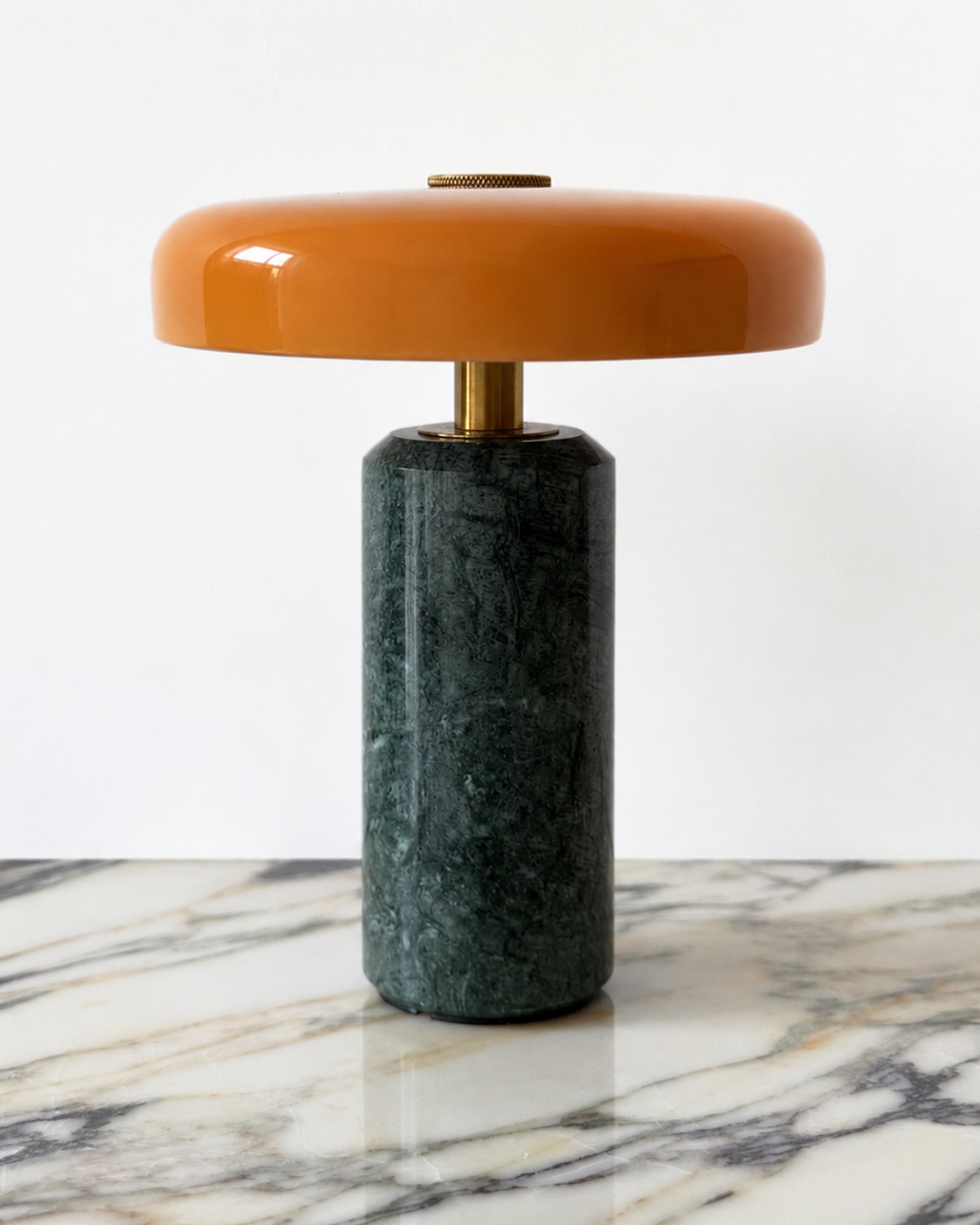 Design-led Muse table lamp featuring a green marble base, brass detailing and a glossy orange rounded shade.